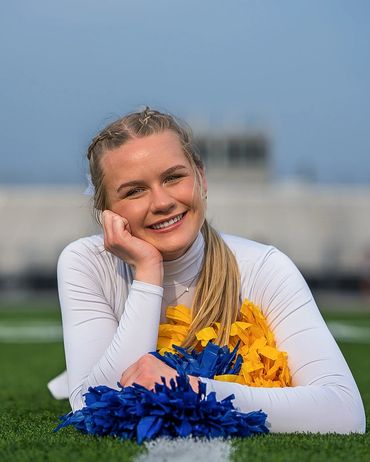 Cheerleader laying on field with pom pom
