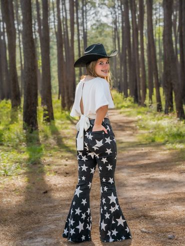 Girl in forest with cowboy hat and stars on jeans