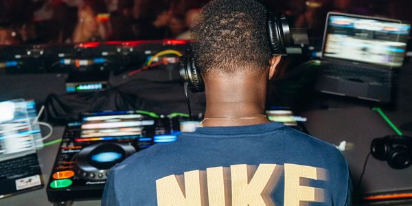 DJ wearing Nike shirt mixing music at a DJ booth.