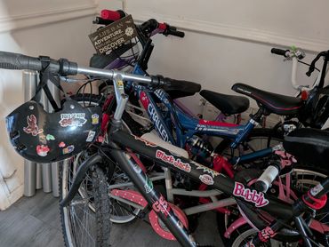 Two colorful bicycles with stickers and a helmet hanging on the handlebar.