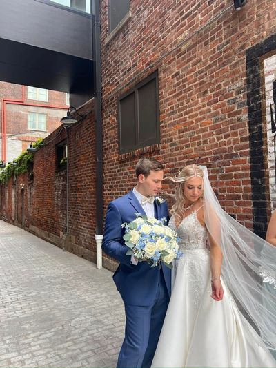 Bride and groom posing outdoors against a brick wall.