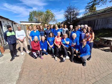 A group of diverse adults posing outdoors on a sunny day.
