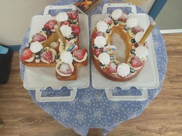 Number 40 shaped cake decorated with cream and strawberries on a blue table.