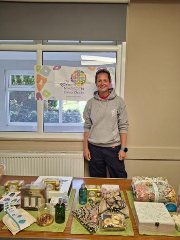 Woman standing behind a table with various items for charity sale.