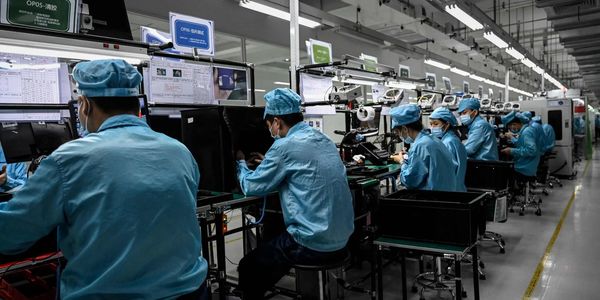 Workers in blue uniforms assembling electronics in a factory line.