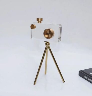 Minimalist clear camera with gold accents on a gold tripod.