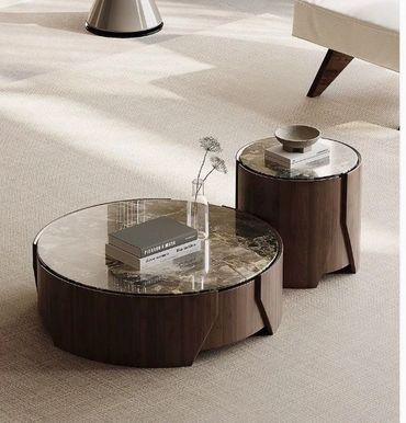 Two round marble-topped wooden coffee tables with books and a vase.