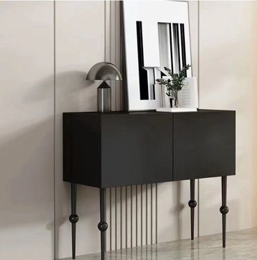 Modern black cabinet with sleek design, decorative lamp, and framed art.