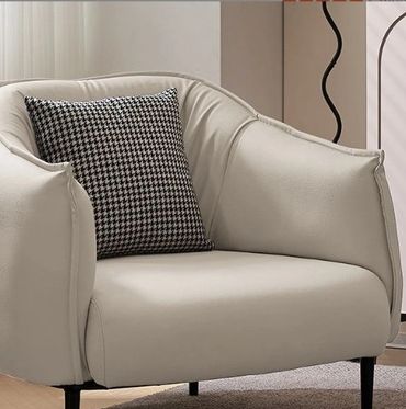 Modern beige armchair with a black and white houndstooth cushion.