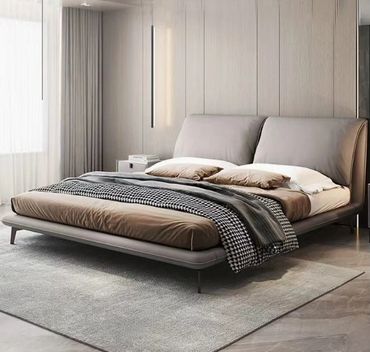 Modern bed with neutral tones and patterned blankets in a stylish bedroom.