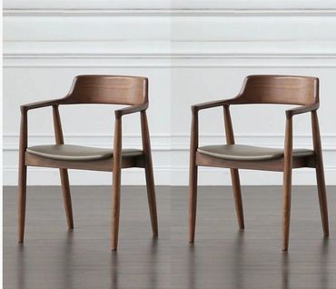 Pair of modern wooden armchairs with leather seats in a minimalistic setting.