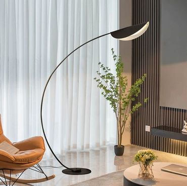 Modern curved floor lamp illuminating a cozy living room corner.