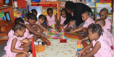Children in pink uniforms playing with blocks in a classroom.