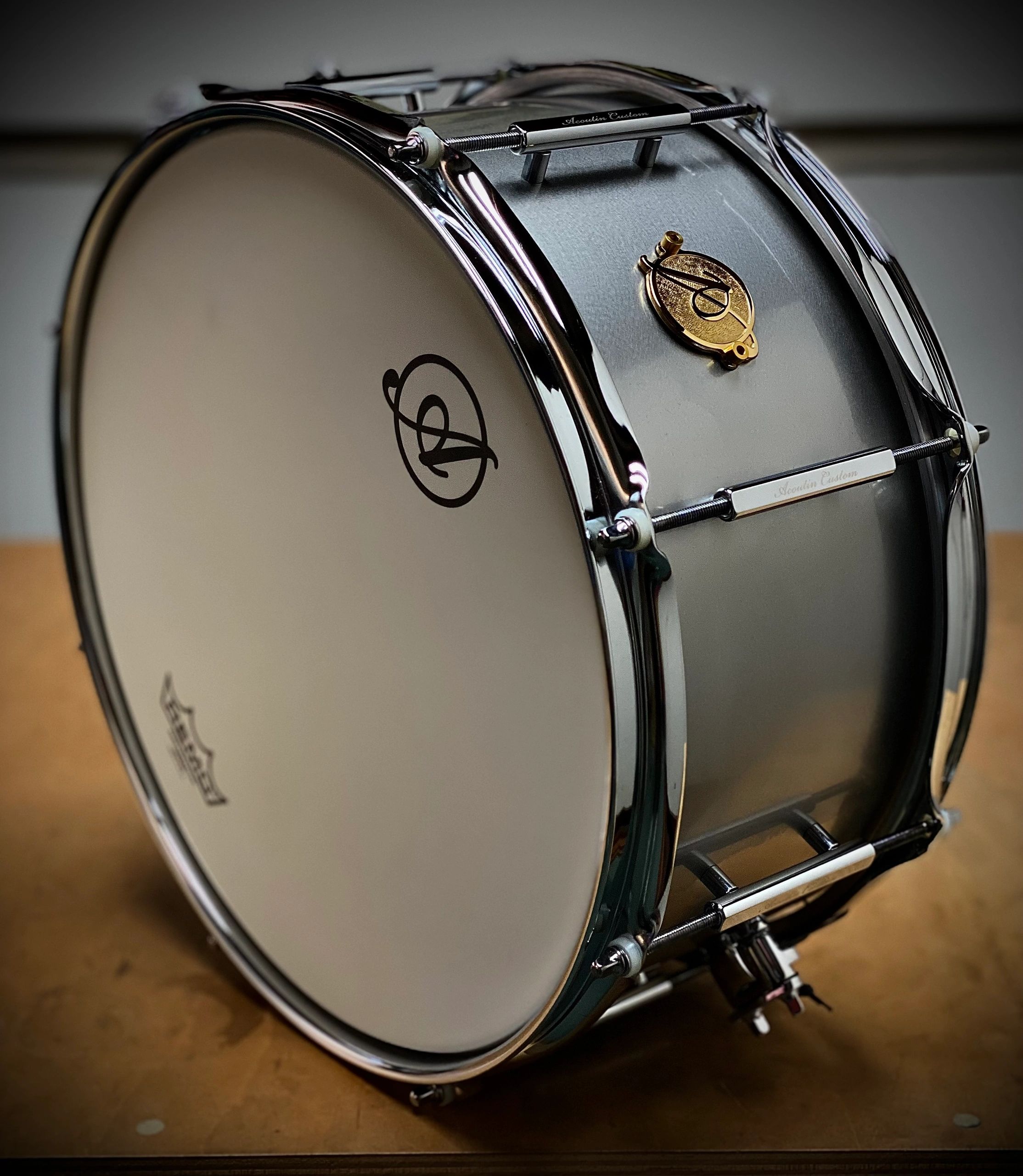 Close-up of a shiny snare drum with chrome hardware and a white drumhead.