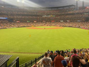 A lively baseball game with a packed stadium under bright lights at dusk.