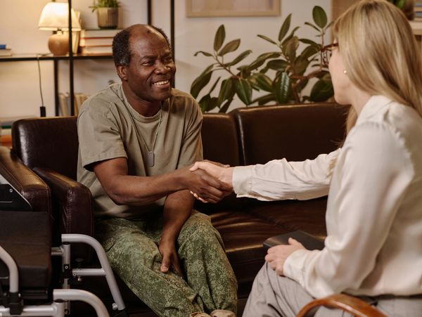 Smiling veteran shaking hands with a counselor.