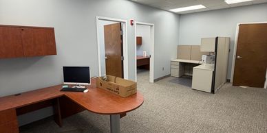 A clean, spacious office with wooden desks and beige chairs.