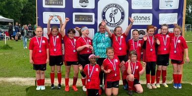 Youth soccer team in red uniforms celebrating with medals.