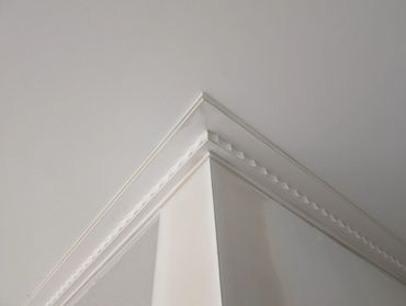 Close-up of a white ceiling corner with decorative molding.
