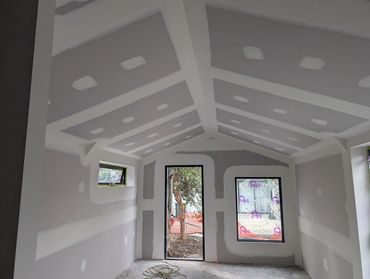 Interior of a room under construction with drywall installed and windows.