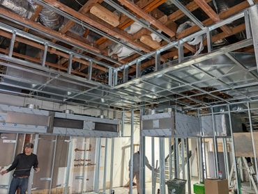 Construction site with exposed ceiling and metal framework installation.