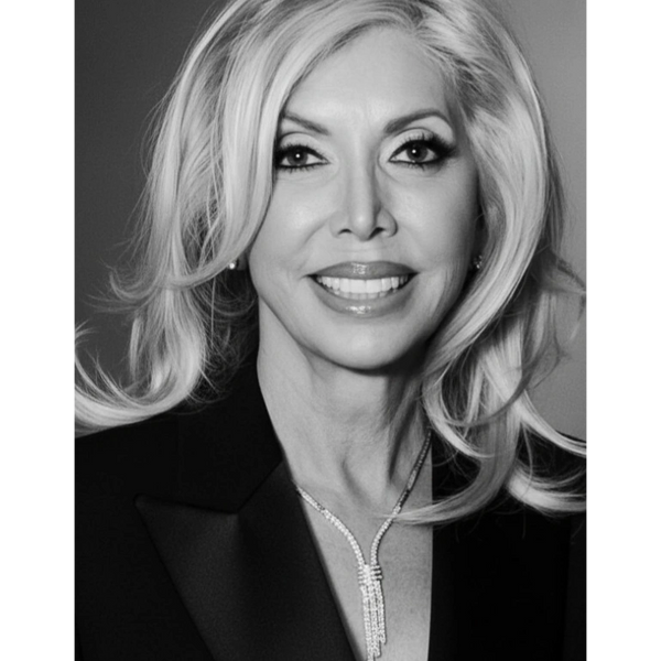 Black and white portrait of a smiling woman with styled blonde hair and elegant jewelry.