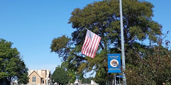 American flag hanging on a pole with a banner beneath it.