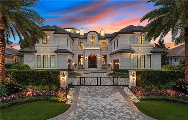 Luxury mansion with elegant driveway and sunset sky.