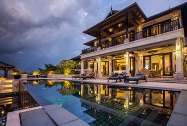 Luxurious villa with illuminated pool at dusk.