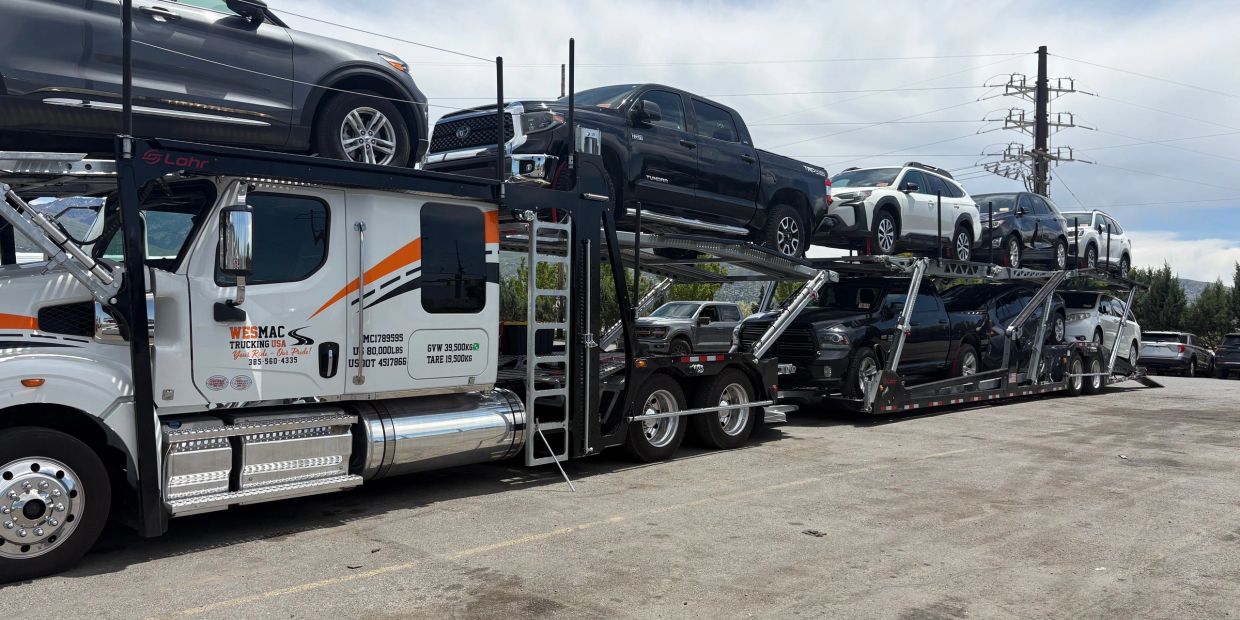 A car carrier truck loaded with multiple vehicles parked outdoors.