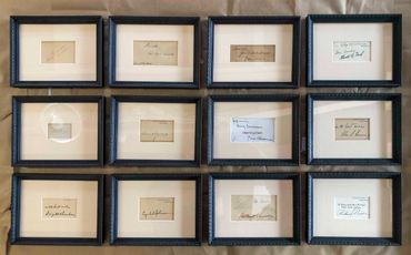 Twelve presidential signatures preserved in ornate black frames with beige mat boards 