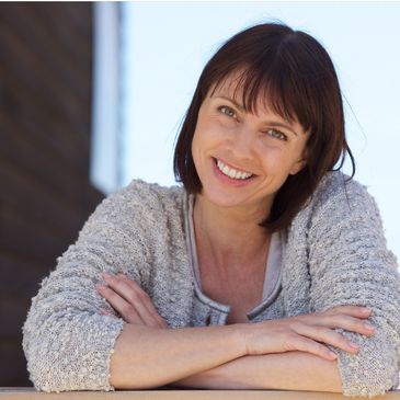 Woman with short brown hair  in her 40's looking happy.