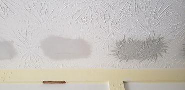Ceiling with water damage stains and textured pattern.