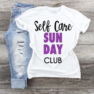 White t-shirt with "Self Care Sunday Club" text paired with ripped blue jeans.
