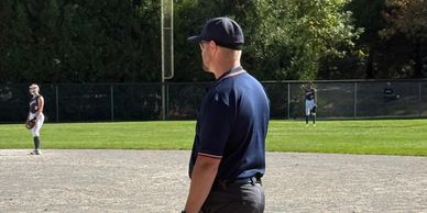 Baseball umpire standing on the field observing the game.