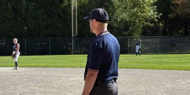 Baseball umpire standing on the field observing the game.
