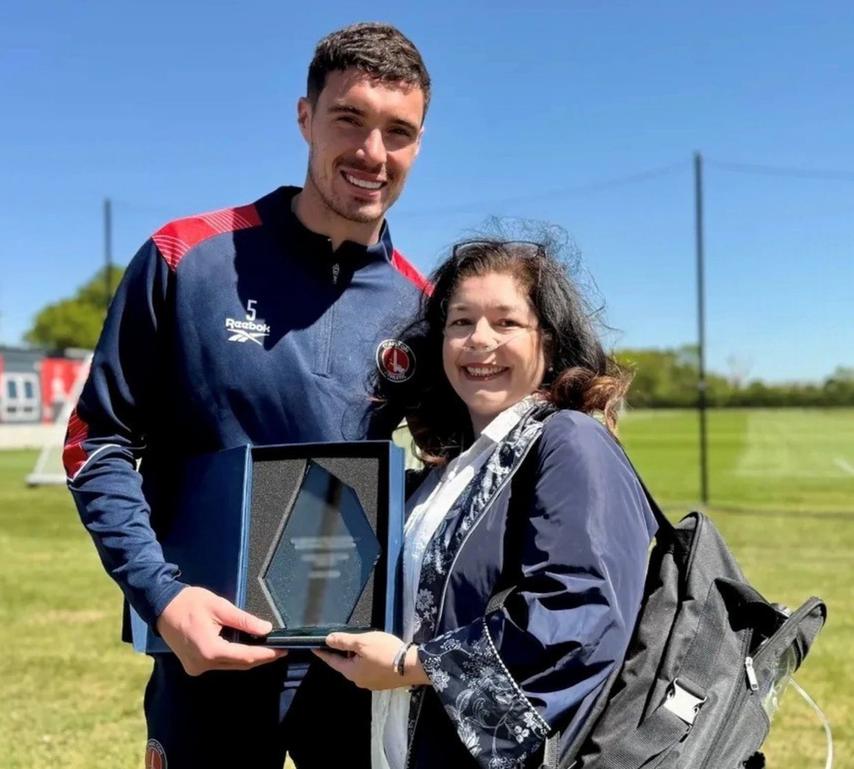 Man and woman holding a glass award outdoors.