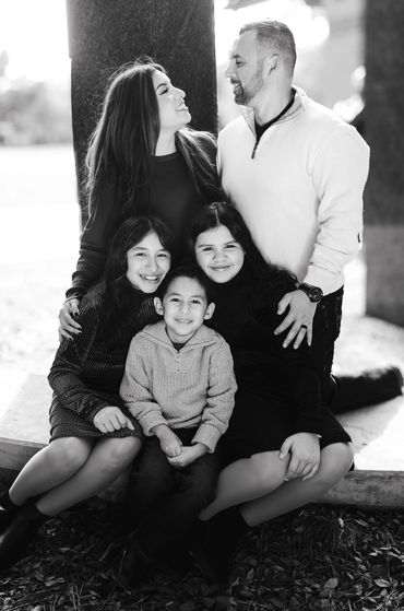 A happy family posing together outdoors in black and white.