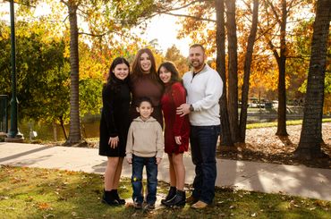 Family posing together outdoors during autumn with colorful leaves.