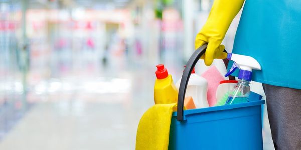 Cleaning lady with a bucket and cleaning products on blurred background.