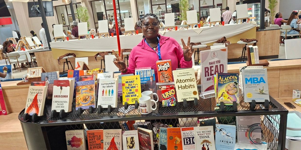 Person posing behind a book and game display in a bookstore.