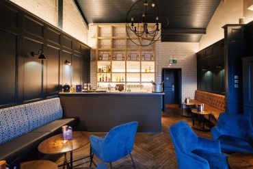 Cozy modern bar with blue chairs and dark wood accents.