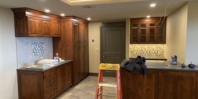 A kitchen under renovation with wooden cabinets and a step ladder.
