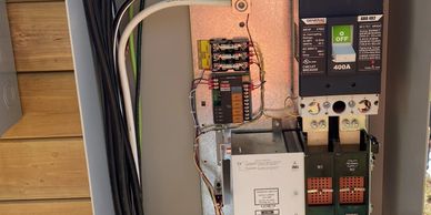 Open electrical panel with circuit breakers and wiring.