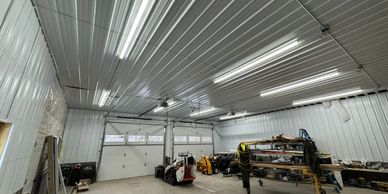 Spacious industrial garage with high ceilings and fluorescent lighting.