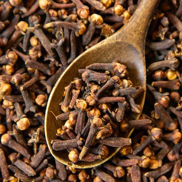 Close-up of dried cloves in a wooden spoon.