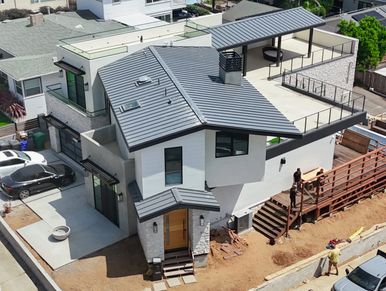Modern house under construction with workers building a wooden pergola on the side.