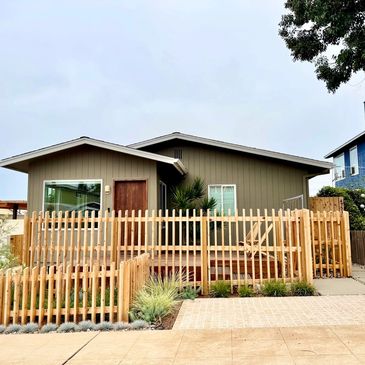 Modern house with wooden fence and deck in front yard.