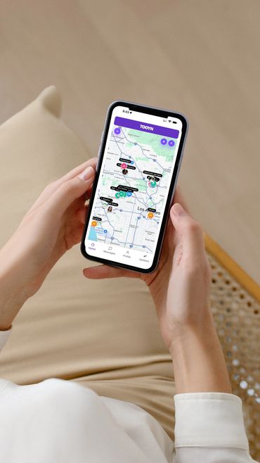 A person holding a phone with TOOYN App on it