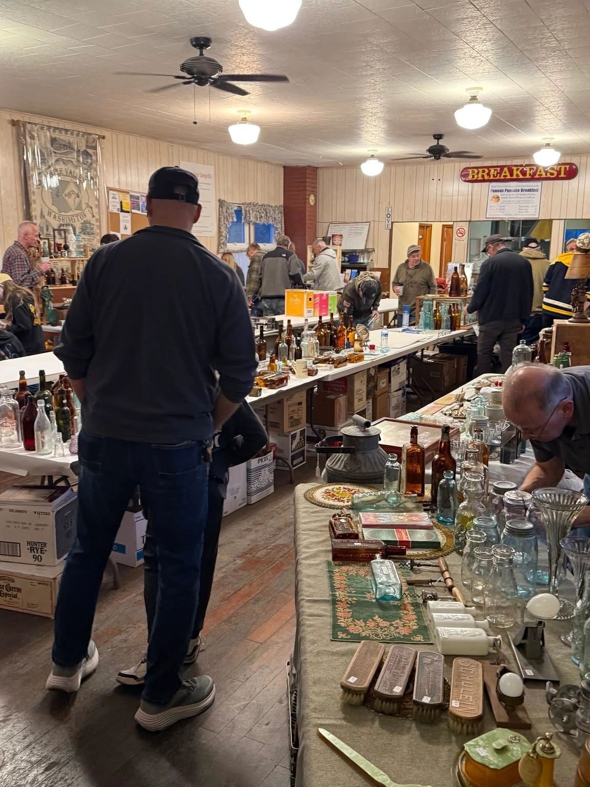 People browsing vintage bottles at a community sale.